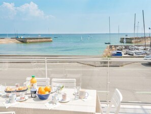 A dining table set with breakfast items, overlooking a marina with boats and a clear sky.