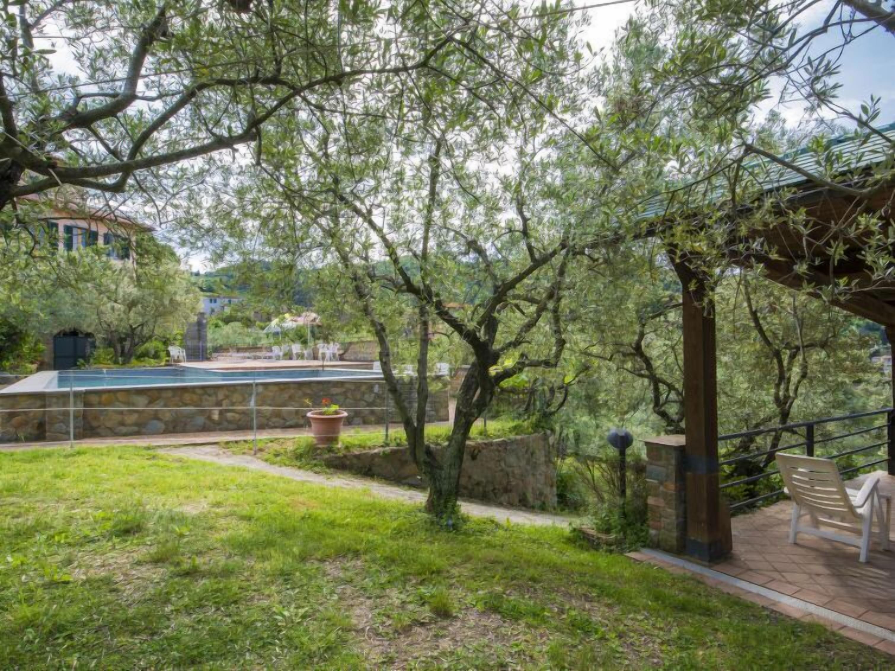 Ein Poolbereich mit Steinwänden, einer Pergola und einer Sitzecke mit Stühlen.