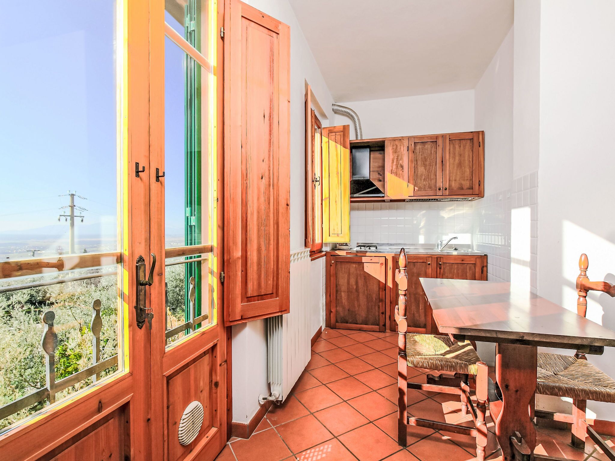 Une cuisine avec des meubles en bois, une table à manger et une vue par la fenêtre.