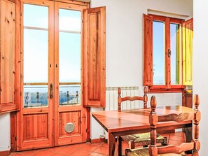 Une table à manger en bois, des chaises, une fenêtre donnant sur un beau paysage et un radiateur.