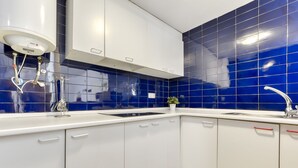 A kitchen with white cabinets, a blue tiled backsplash, a stainless steel sink, and a white countertop. - Platja de Roses by Interhome (Roses)