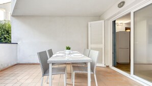 A dining area with a table set for four, surrounded by wicker chairs, on a tiled floor. - Platja de Roses by Interhome (Roses)