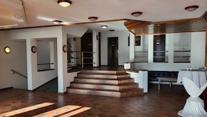 Un vestíbulo amplio con una escalera, un mostrador de recepción y una zona de estar.