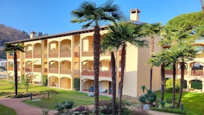 Un hotel de varios pisos con un patio central, palmeras y un jardín bien cuidado.