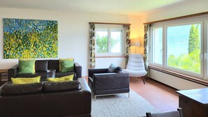 Ein Wohnzimmer mit einer Couch, Sesseln, einem Couchtisch und einem Bild an der Wand.