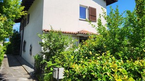 Ein zweistöckiges Gebäude mit weißer Fassade, einem Ziegeldach und einem kleinen Fenster mit Fensterläden.