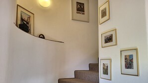 Eine Treppe mit mehreren Stufen, die nach oben führt, gesäumt von Wänden mit gerahmten Bildern.