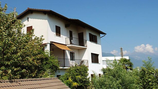 Ein zweistöckiges Gebäude mit Balkon und Satellitenschüssel.