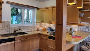 Eine Küche mit Holzausstattung, einem Fenster und einer Arbeitsplatte mit Kaffeemaschine.