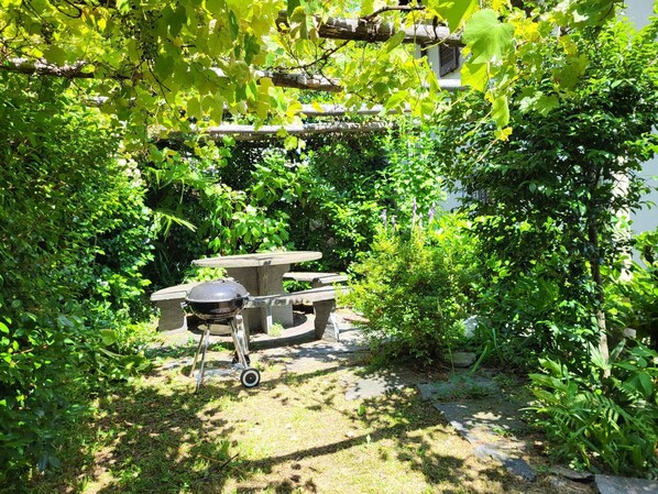 A garden with a barbecue grill and stone seating.