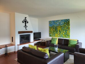 Una sala de estar moderna con chimenea, televisor de pantalla plana, conjunto de sofá y un cuadro abstracto colorido.