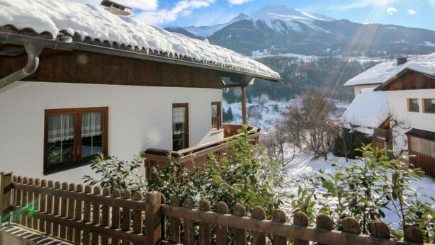 Eine Chalet mit Holzbalkon, weißen Wänden und einem mit Schnee bedeckten Dach.