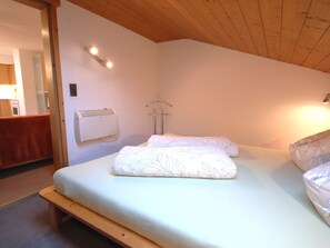 Una camera da letto con un letto, una panca in legno, un condizionatore d'aria a parete e un porta asciugamani.
