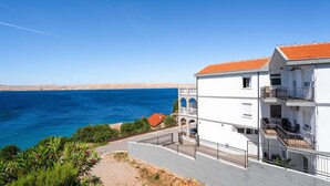 A coastal building with balconies, a clear blue sea, and a hilly backdrop. - Apartment Delfin by Interhome (Karlobag)