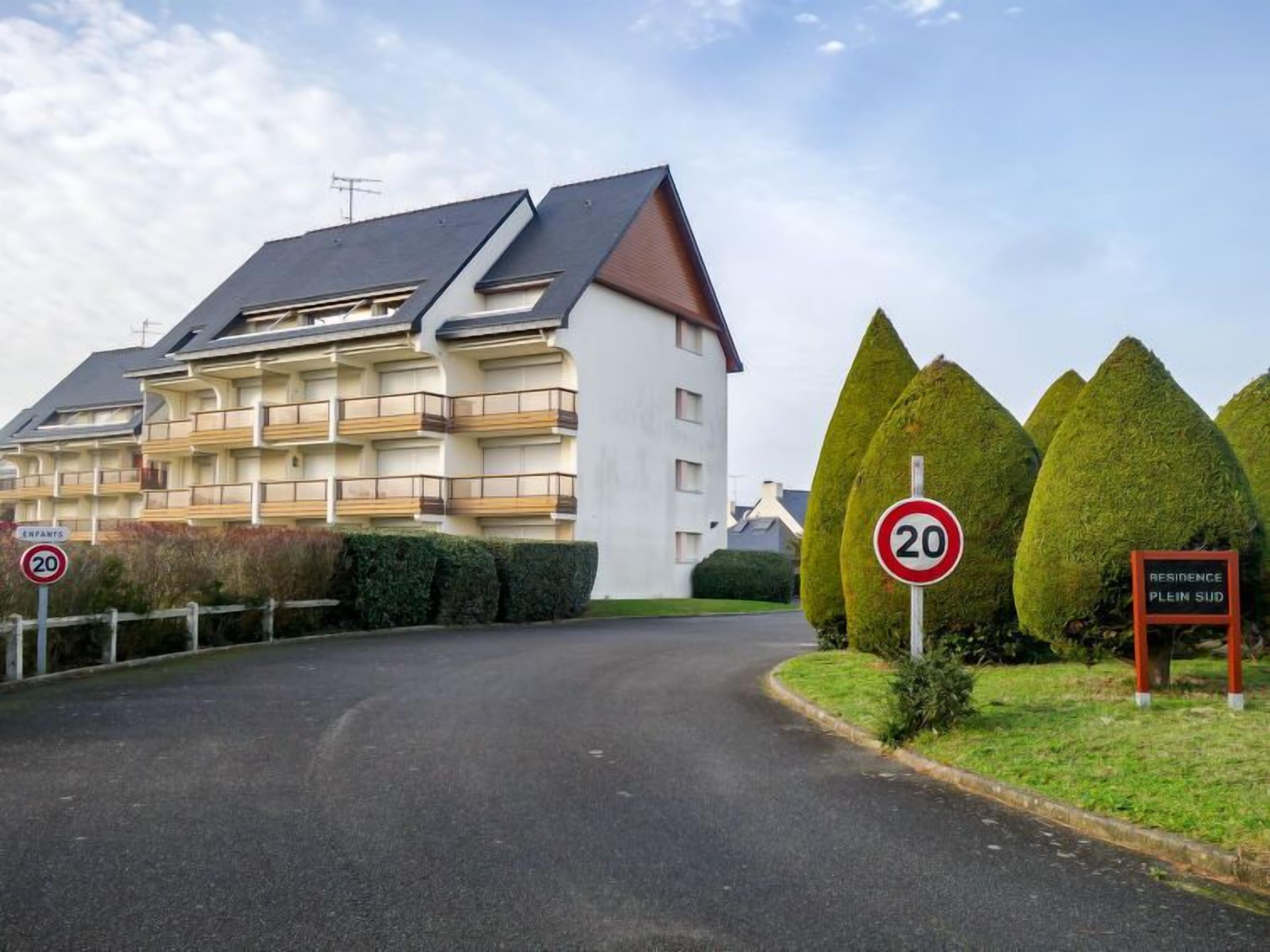Un immeuble résidentiel au design moderne, doté de nombreux balcons et d’un toit en pente.