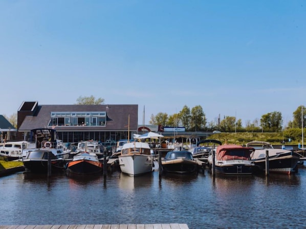 Ein Yachthafen mit verschiedenen vertäuten Booten, ein modernes Gebäude mit großen Fenstern und ein klarer Himmel.