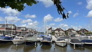 A marina with boats docked, surrounded by residential buildings with sloped roofs and large windows. - Busch en Dam by Interhome (Uitgeest)