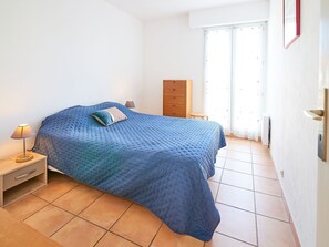 A bedroom with a bed, a nightstand, a dresser, and a window with curtains. - Cap Hermes by Interhome (Fréjus)