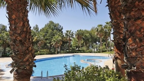 Une piscine entourée de palmiers et de verdure.