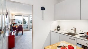 Een moderne keuken met witte kasten, een granieten aanrecht en een houten eettafel.