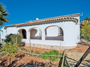 A white building with a tiled roof and three arched windows.