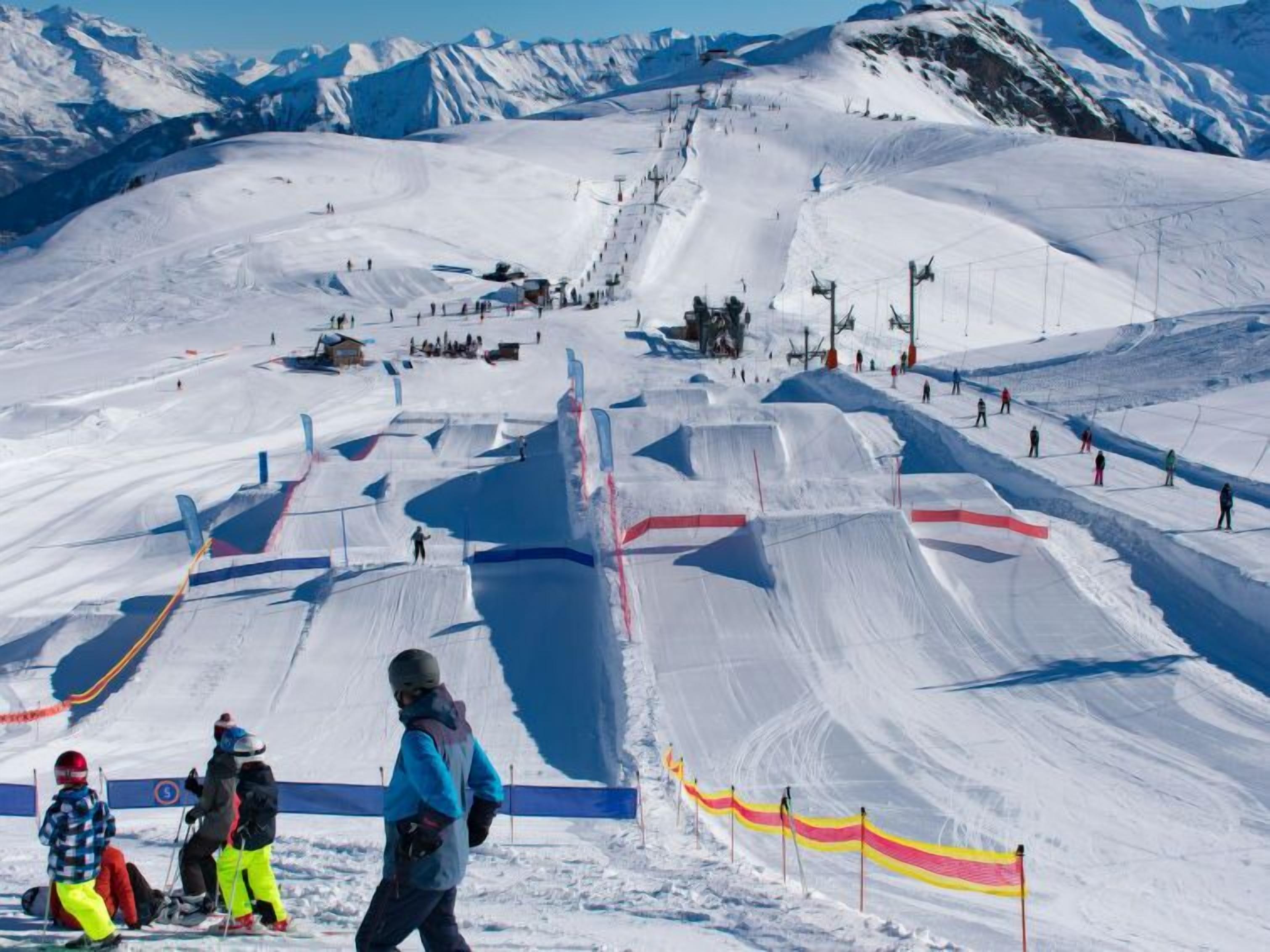 A snow-covered ski slope with marked paths and a ski lift in the background.