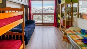 A room with bunk beds, a desk with a chair, and a window with a mountain view. - Soyouz Vanguard by Interhome (Le Corbier)