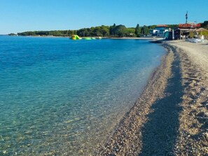 A beach with clear water, pebbles, and a building labeled "Beach Bar" in the background. - Villa Fasana by Interhome (Fažana)