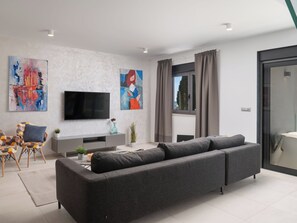 A modern living room with a grey sofa, a flat-screen TV, abstract art, and a window with curtains. - Villa Fasana by Interhome (Fažana)