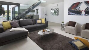 Un salon moderne avec un canapé gris, une table basse et un escalier menant à un niveau supérieur.