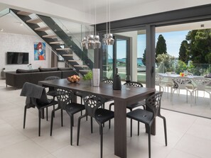 Een moderne eethoek met een grote tafel, stoelen en een trap naar een balkon met uitzicht.