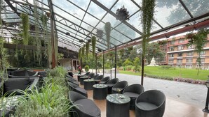 A covered outdoor seating area with wicker furniture and hanging plants. - The Malla Hotel (Kathmandu)