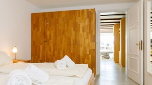 A hotel room with a wooden wardrobe, a bed with white linens, and a nightstand with a lamp. - Residenza Chesa Margun 58-5 by Interhome (Silvaplana-Surlej)