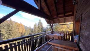 A wooden deck with a bench and a table, overlooking a forested area. - Wassertheureralm by Interhome (Dellach)