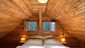A cozy attic bedroom with a sloped ceiling, two windows, a bed with white linens, and two bedside lamps. - Wassertheureralm by Interhome (Dellach)