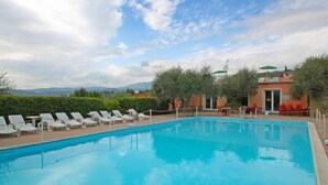 A swimming pool with lounge chairs, a building with a red roof, and a mountainous backdrop. - Borgoverde by Interhome (Imperia)