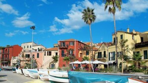 A row of boats parked along a waterfront, with colorful buildings and palm trees in the background. - Borgoverde by Interhome (Imperia)