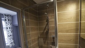 Ein modernes Badezimmer mit einer gläsernen Dusche, einem weißen Waschbecken und Holzvertäfelung an den Wänden.