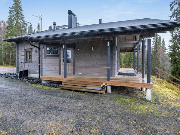 En stuga med en träveranda, en skorsten och en inglasad veranda.