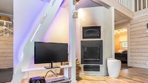 En moderne stue med et fladskærms-tv på et hvidt stativ, en pejs og et hyggeligt siddeområde.