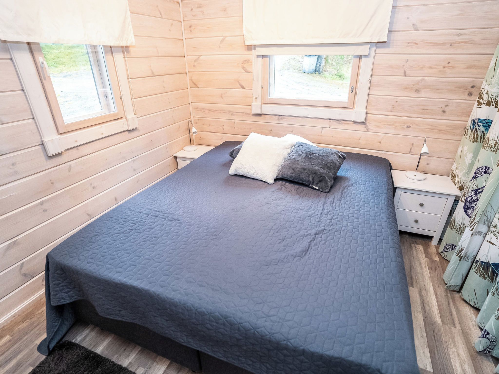 A room with a bed, a nightstand, and a window with curtains.