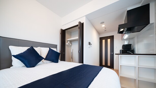 A modern hotel room with a large bed, a wardrobe, and a kitchenette. - Grandouce Juso (Osaka)