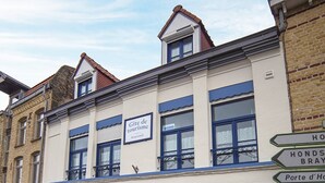 Un edificio con un letrero que indica 'Gîte de tourisme' y señales direccionales hacia 'Hond's Bray' y 'Porte d'Ho'.