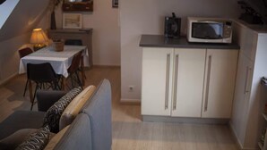 Una cocina compacta con microondas, una mesa de comedor con sillas y un sofá.