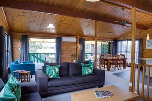 A wooden interior with a sofa, chairs, and a dining table.