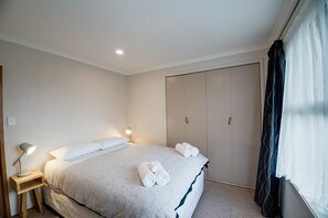 A bedroom with a bed, bedside lamps, a wardrobe, and a window with curtains. - Leo's Place - Hot Tub, Ride to Redwoods, Sleeps 9 (Lynmore)