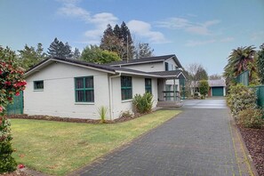 A single-story residential building with a paved driveway and a green lawn. - Leo's Place - Hot Tub, Ride to Redwoods, Sleeps 9 (Lynmore)