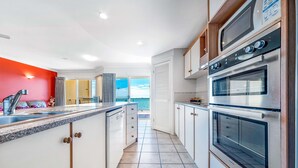 A modern kitchen with white cabinets, a granite countertop, and stainless steel appliances including a double oven. - Ocean Views Galore - Airlie Beach (Cannonvale)