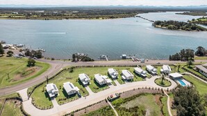 An aerial view of a lakeside property with several white buildings arranged in a semi-circular pattern around a central lawn area.