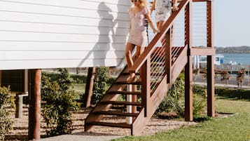 A white building with a wooden staircase leading to a covered area.